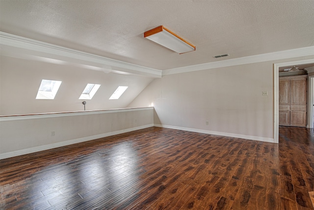 unfurnished room with vaulted ceiling with skylight, crown molding, dark hardwood / wood-style flooring, and a textured ceiling