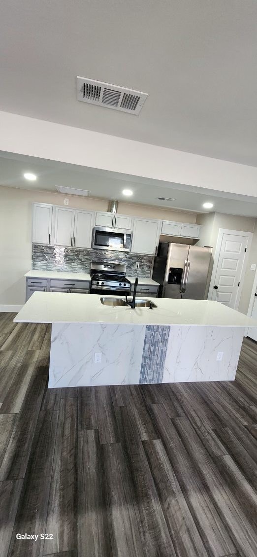 kitchen featuring appliances with stainless steel finishes, dark hardwood / wood-style flooring, tasteful backsplash, sink, and white cabinetry