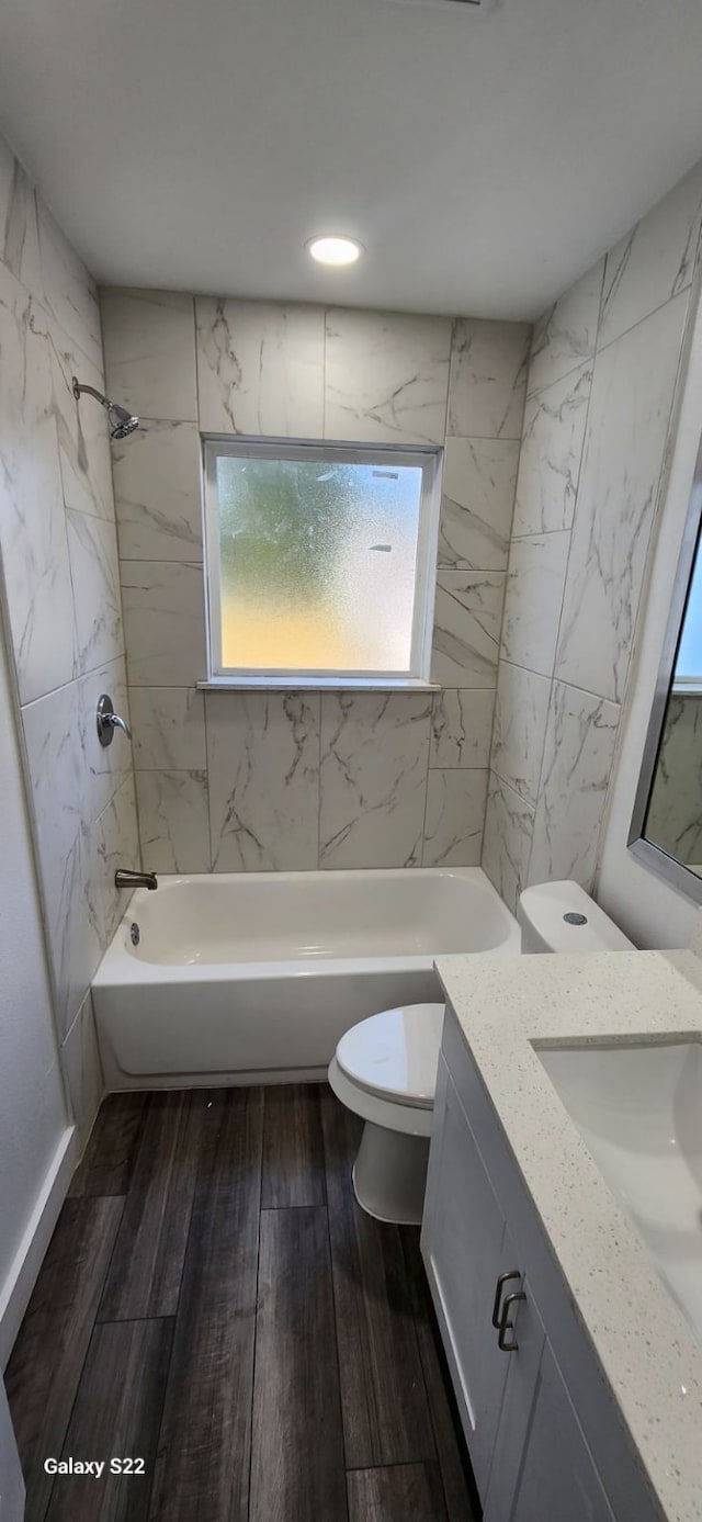 full bathroom featuring toilet, hardwood / wood-style floors, vanity, and tiled shower / bath combo