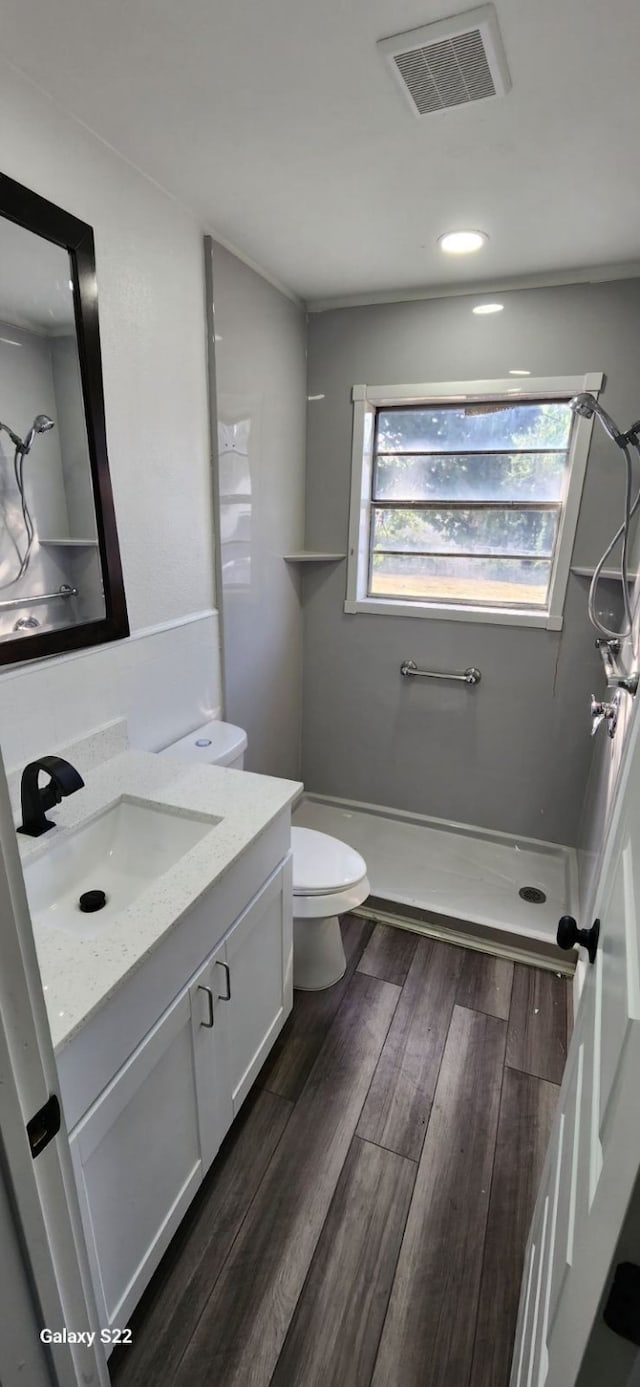 bathroom featuring vanity, hardwood / wood-style flooring, toilet, and walk in shower