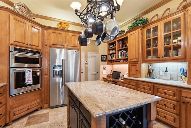 kitchen featuring light stone countertops, backsplash, appliances with stainless steel finishes, a kitchen island, and ornamental molding