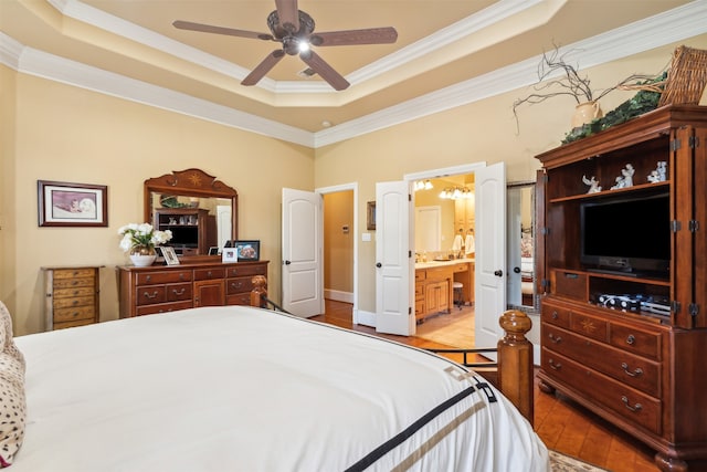 bedroom with ceiling fan, ensuite bathroom, crown molding, light hardwood / wood-style floors, and a tray ceiling