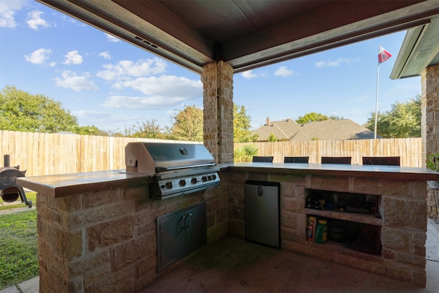 view of patio featuring exterior kitchen and a grill