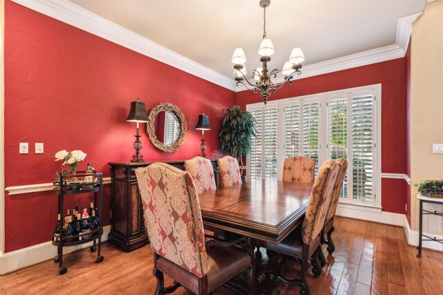 dining area with hardwood / wood-style flooring, a notable chandelier, and ornamental molding