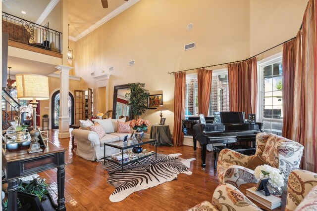 living room with a high ceiling, hardwood / wood-style flooring, ornate columns, and crown molding