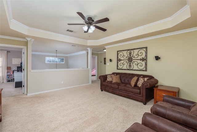 carpeted living room with a tray ceiling, ceiling fan, ornamental molding, and decorative columns