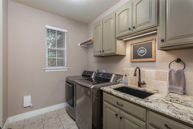 washroom featuring cabinets, light tile patterned floors, washing machine and dryer, and sink