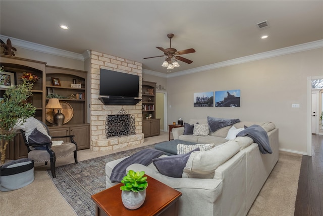 living room featuring ceiling fan, a fireplace, crown molding, and light hardwood / wood-style flooring