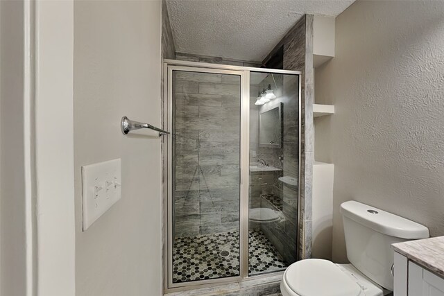 bathroom featuring an enclosed shower, vanity, toilet, and a textured ceiling