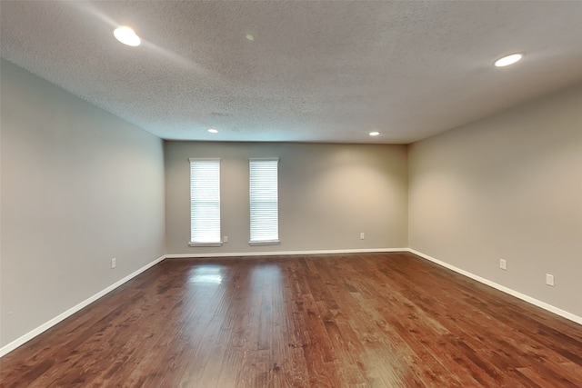 spare room featuring dark hardwood / wood-style flooring and a textured ceiling