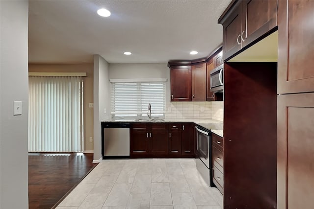 kitchen featuring light stone countertops, sink, tasteful backsplash, light hardwood / wood-style floors, and appliances with stainless steel finishes