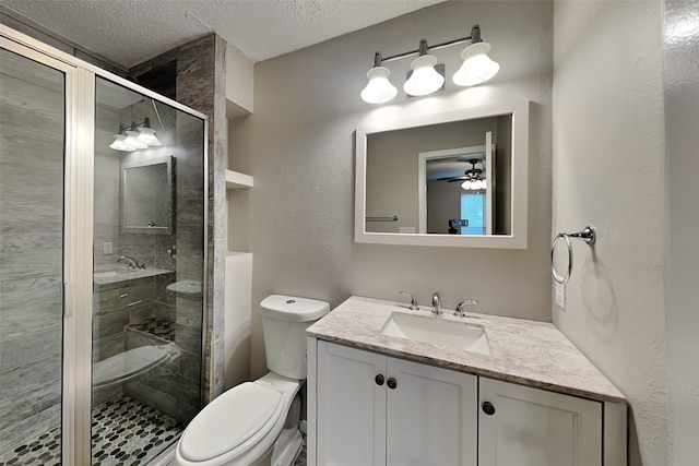 bathroom with vanity, a textured ceiling, ceiling fan, toilet, and a shower with shower door