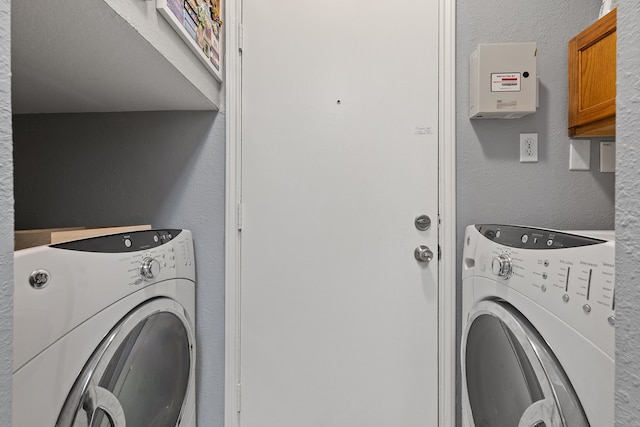 clothes washing area with cabinets and washing machine and clothes dryer