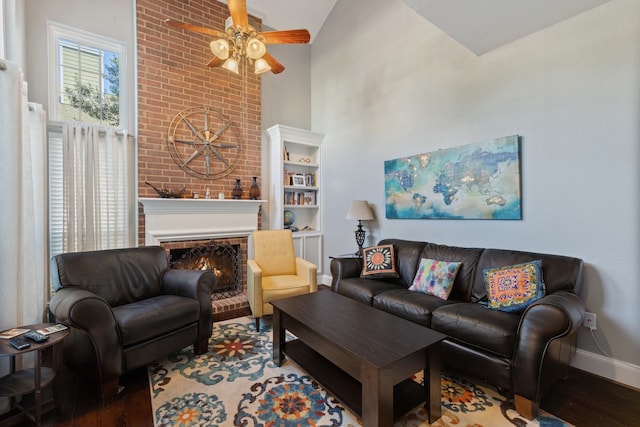 living room featuring hardwood / wood-style floors, high vaulted ceiling, a brick fireplace, and ceiling fan