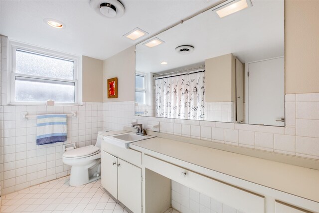 bathroom with vanity, toilet, tile walls, and a healthy amount of sunlight