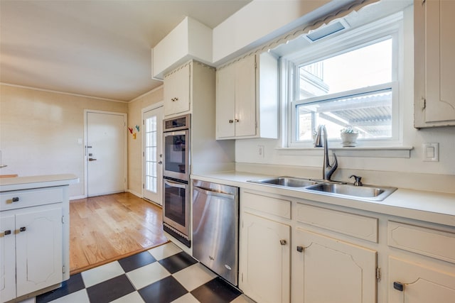 kitchen with white cabinets, stainless steel appliances, light hardwood / wood-style floors, and sink