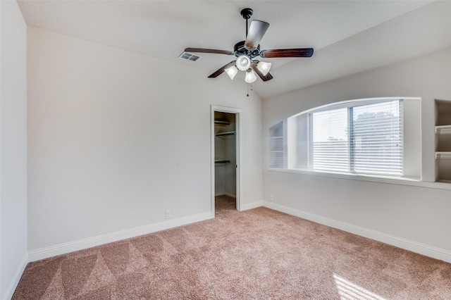 unfurnished bedroom with ceiling fan, a spacious closet, vaulted ceiling, light carpet, and a closet