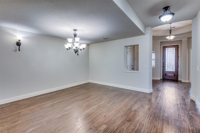 foyer featuring dark hardwood / wood-style flooring, a textured ceiling, and a chandelier