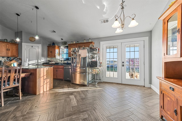 kitchen featuring french doors, lofted ceiling, stainless steel appliances, and pendant lighting