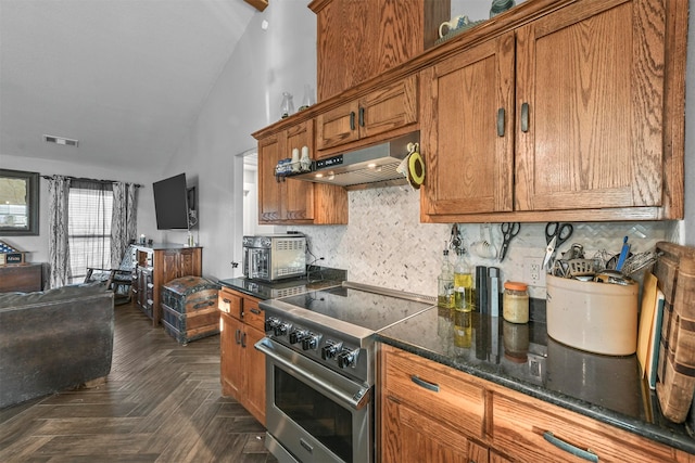 kitchen with stainless steel range, range hood, backsplash, dark stone countertops, and lofted ceiling