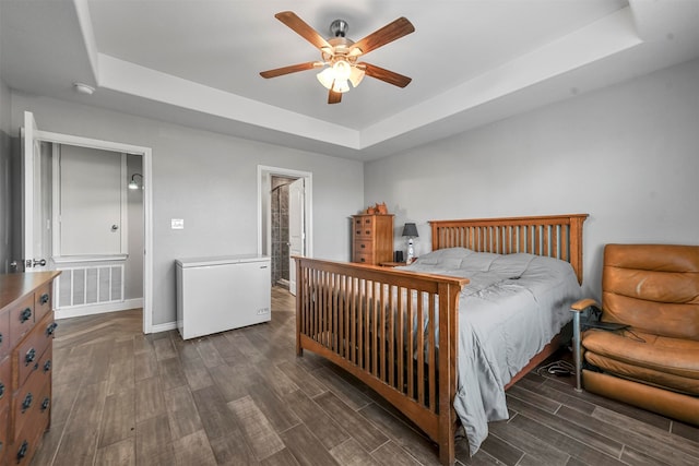 bedroom featuring a raised ceiling, ceiling fan, and dark hardwood / wood-style floors