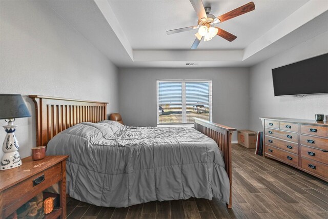 bedroom featuring a raised ceiling, ceiling fan, and dark wood-type flooring