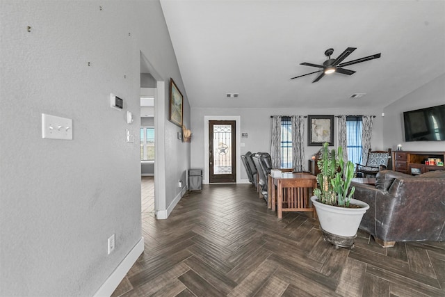 living room with dark parquet flooring, ceiling fan, plenty of natural light, and vaulted ceiling