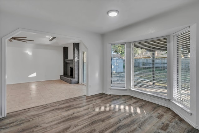 unfurnished living room featuring ceiling fan, light hardwood / wood-style floors, and a wealth of natural light