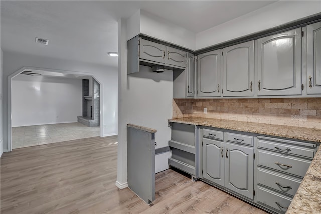 kitchen with light stone countertops, a fireplace, and light wood-type flooring