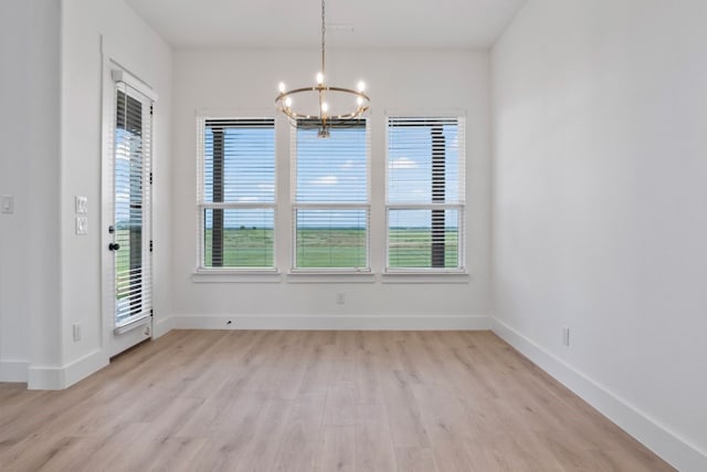 unfurnished dining area with a notable chandelier and light hardwood / wood-style floors