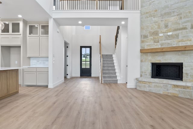 interior space with light wood-type flooring, a fireplace, and a high ceiling