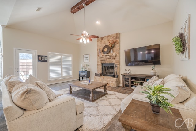 living room with high vaulted ceiling, a stone fireplace, ceiling fan, beamed ceiling, and wood-type flooring