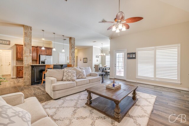 living room with ceiling fan with notable chandelier, dark hardwood / wood-style flooring, and ornamental molding