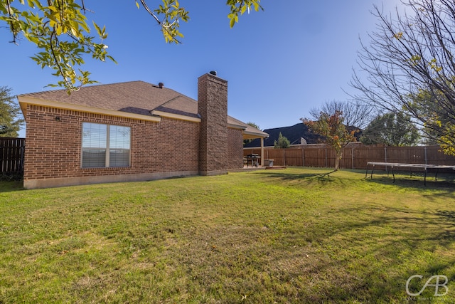 view of yard with a trampoline and a patio