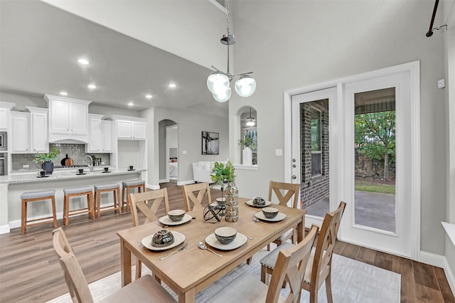 dining space with light hardwood / wood-style floors, sink, and a chandelier