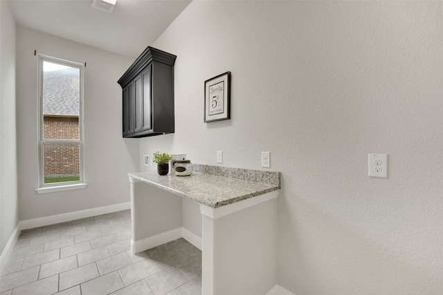 interior space featuring hookup for a washing machine, plenty of natural light, light tile patterned floors, and cabinets