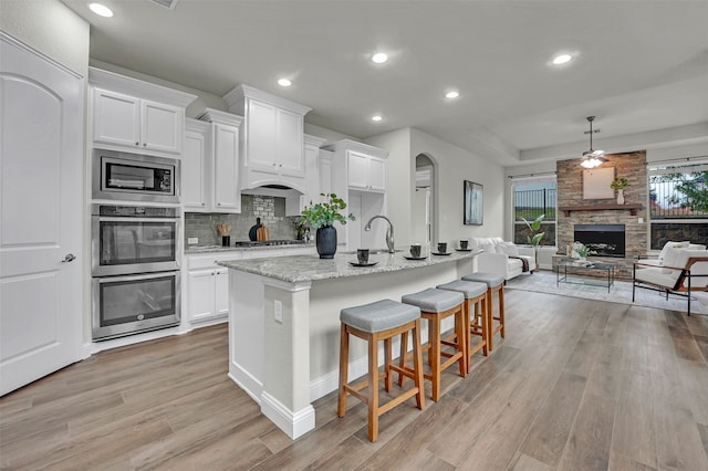 kitchen featuring white cabinets, light wood-type flooring, and an island with sink