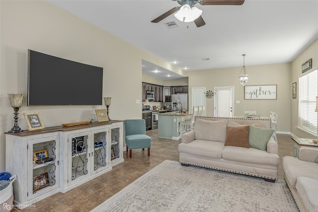 living room with ceiling fan with notable chandelier