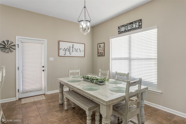 dining room featuring dark tile patterned flooring and a notable chandelier