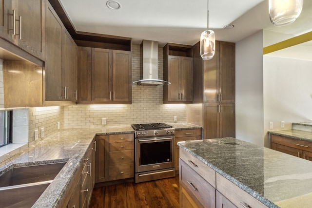 kitchen featuring stone counters, wall chimney range hood, stainless steel gas range, dark hardwood / wood-style floors, and decorative backsplash