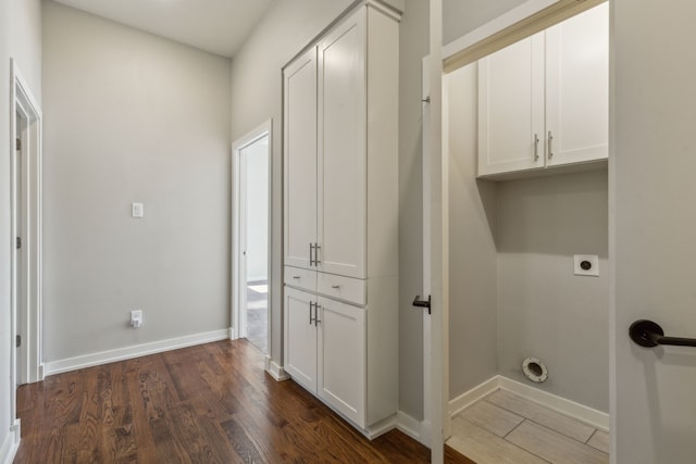 washroom with cabinets, electric dryer hookup, and dark wood-type flooring