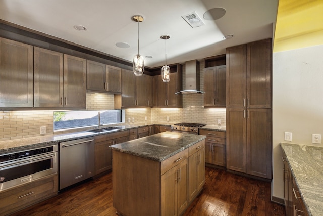 kitchen featuring dark stone countertops, dark hardwood / wood-style flooring, wall chimney exhaust hood, and appliances with stainless steel finishes