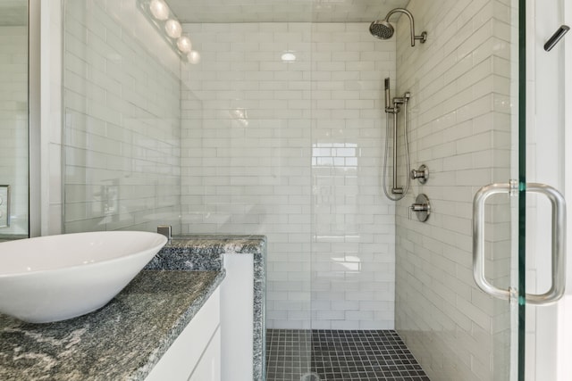 bathroom with a shower with shower door and sink