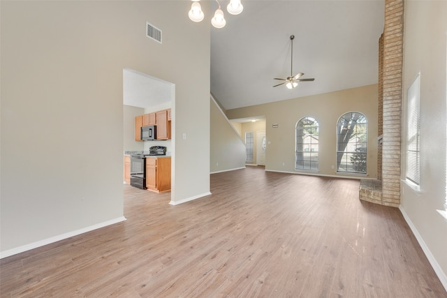 unfurnished living room featuring light hardwood / wood-style flooring, high vaulted ceiling, and ceiling fan with notable chandelier