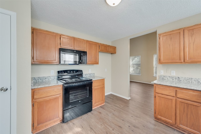 kitchen with black appliances, light wood-type flooring, and a textured ceiling