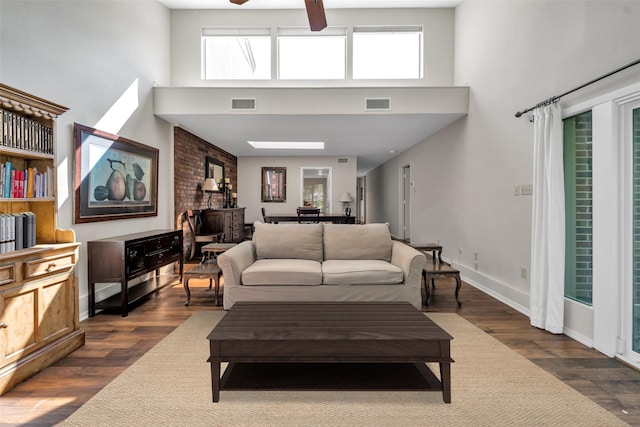 living room with dark hardwood / wood-style floors, ceiling fan, a high ceiling, and a wealth of natural light