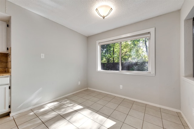 spare room featuring light tile patterned flooring and a textured ceiling