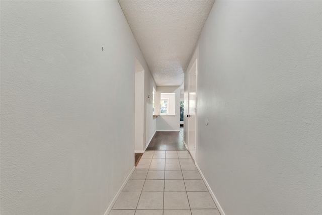 hall featuring light tile patterned flooring and a textured ceiling