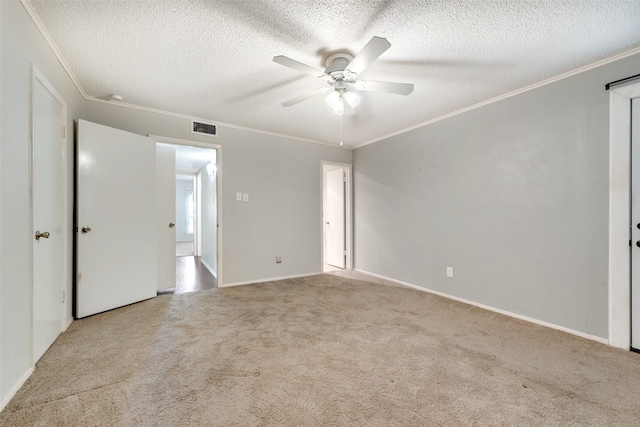 carpeted spare room with ceiling fan, ornamental molding, and a textured ceiling