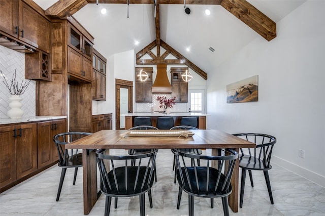 dining space featuring beam ceiling and high vaulted ceiling